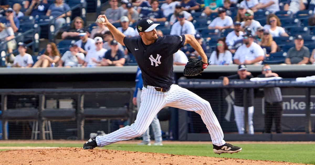 Yankees pitcher throwing a pitch on the mound with a cheering crowd in the stands behind him